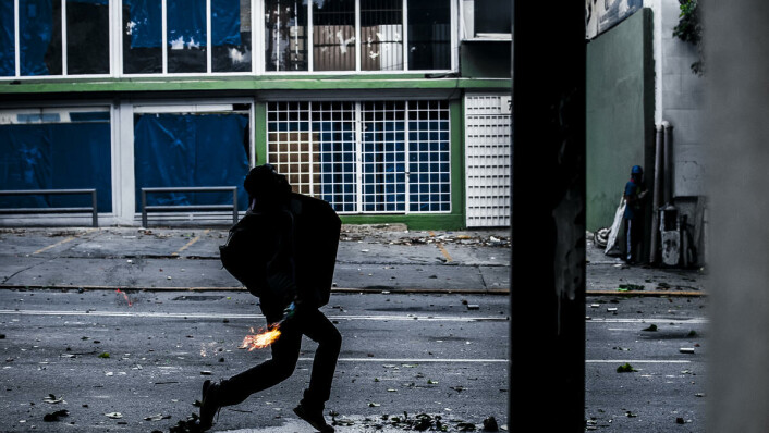 Flaskeangrep: En demonstrant har tent på en glassflaske i sammenstøtene i Venezuela. Flaskeangrep: En demonstrant har tent på en glassflaske i sammenstøtene i Venezuela.