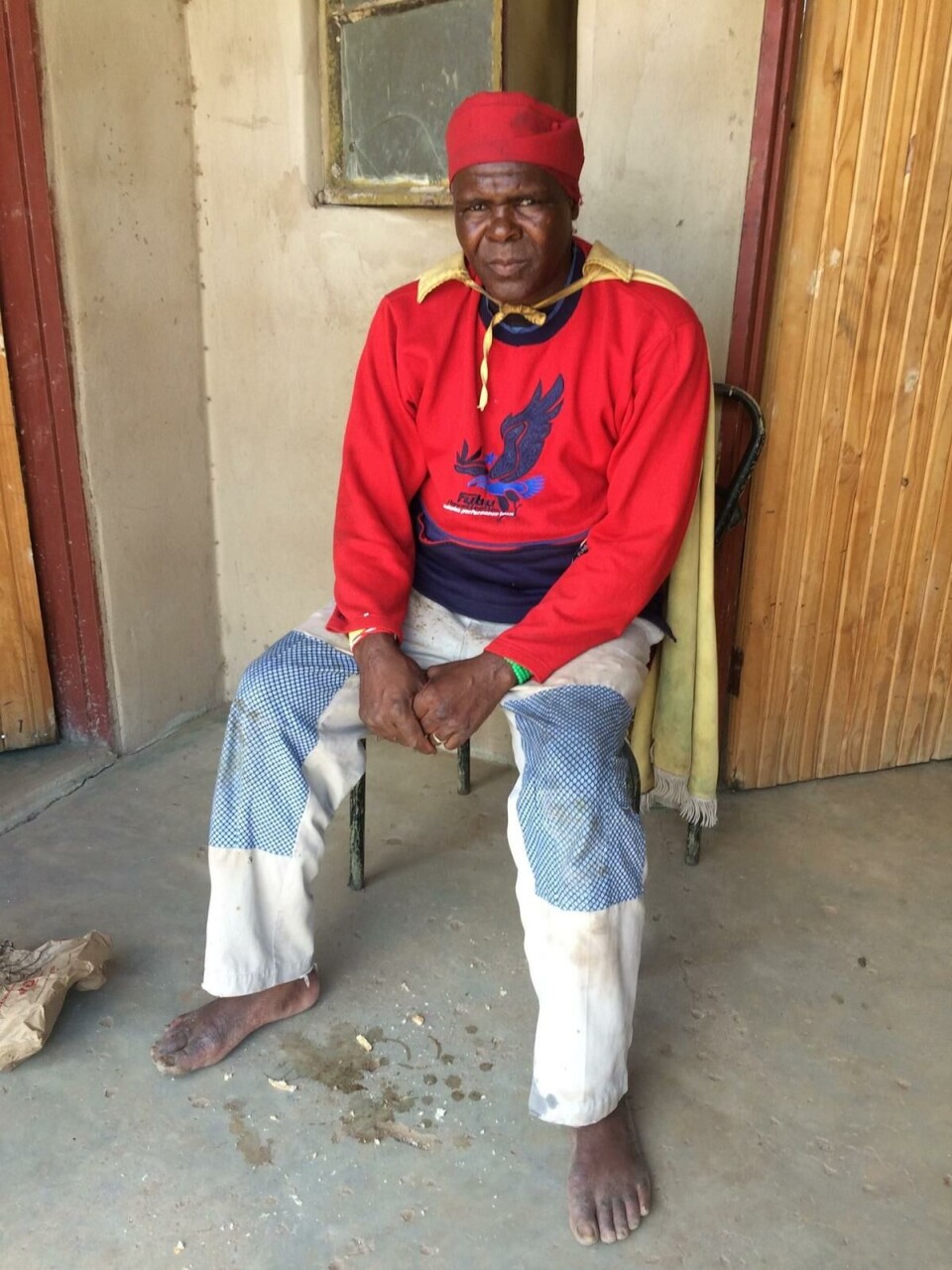 HEKSEDOKTOR: Denne mannen er en heksedoktor. På kappen hans er det brodert et kors. Han er en blanding av en _ngaka ya setswana_, en som driver med hekseri og forfedredyrking, og en _ngaka ya segoma_, som leger med hellig vann og bibelsitater. Lokalbefolkningen mener kombinasjonen gjør han ekstra potent som doktor.