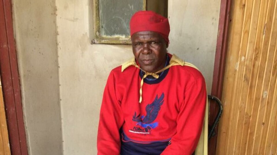 HEKSEDOKTOR: Denne mannen er en heksedoktor. På kappen hans er det brodert et kors. Han er en blanding av en _ngaka ya setswana_, en som driver med hekseri og forfedredyrking, og en _ngaka ya segoma_, som leger med hellig vann og bibelsitater. Lokalbefolkningen mener kombinasjonen gjør han ekstra potent som doktor.