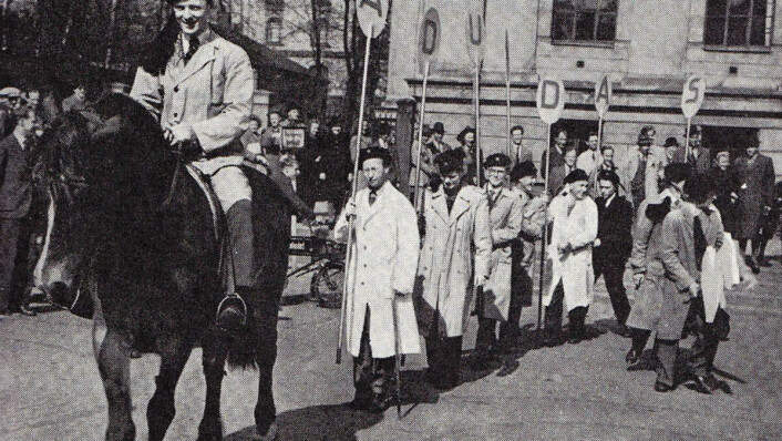 AD UNDAS: Mentz Schulerud bærer det første skiltet når studentene reklamerer for revyen Ad Undas på Karl Johan i 1946. AD UNDAS: Mentz Schulerud bærer det første skiltet når studentene reklamerer for revyen Ad Undas på Karl Johan i 1946.