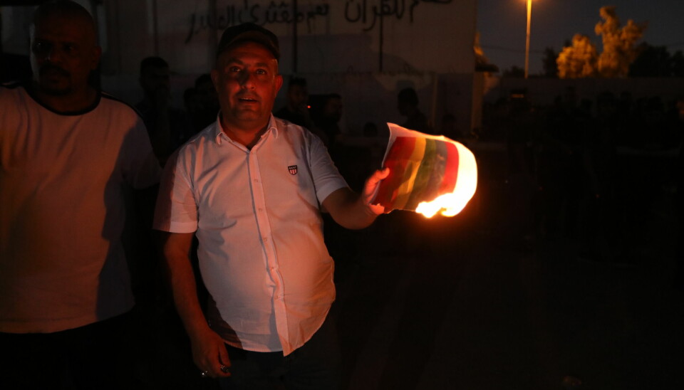 Brennes: En mann brenner et regnbueflagg utenfor den svenske ambassaden i Bagdad 29. juni.