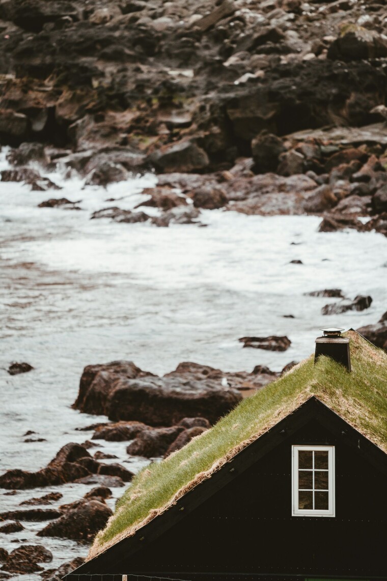 A black house sulks by the sea.