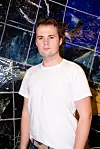Sander vestby, portrettert foran en mosaistisk vegg. Seriøst uttrykk.