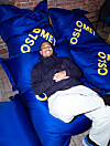 Yosef Ihdego ligger på blå puter med OsloMet-logo innendørs.