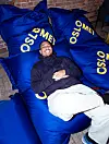 Yosef Ihdego ligger på blå puter med OsloMet-logo innendørs.