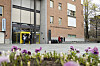 Blomsterbed foran universitetsbygninger ved UiO på Blindern, med mennesker ved inngangen.