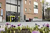 Blomsterbed foran universitetsbygninger ved UiO på Blindern, med mennesker ved inngangen.