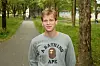 Alan står på en trekledd gangvei iført grå genser med A Bathing Ape-motiv.